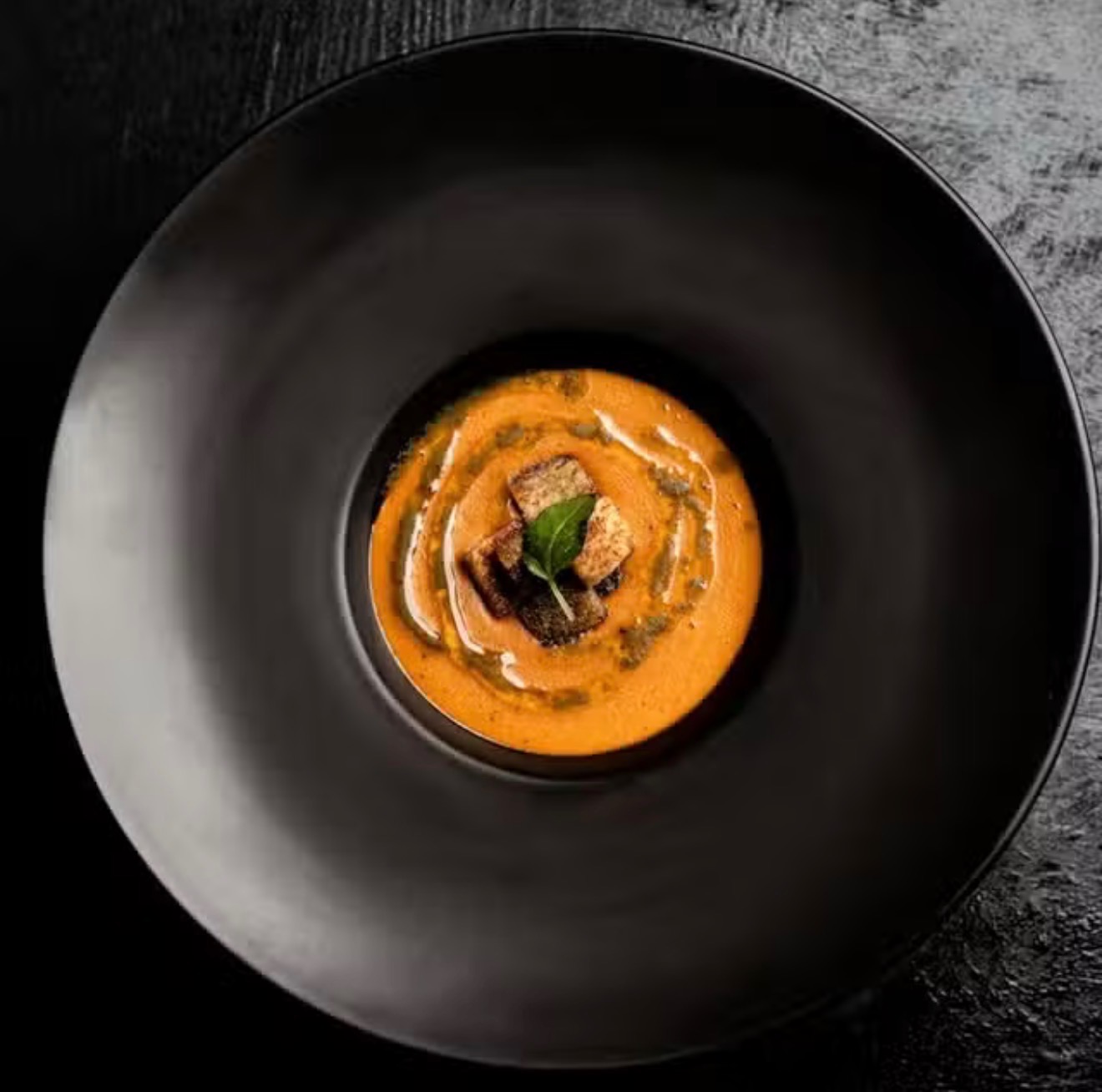 Spiced West African velouté plated on matte black ceramic